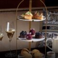 Afternoon tea at the Four Seasons Hotel Prague with cakes, pastries, and hot chocolate served in the elegant flower-filled lobby in winter.