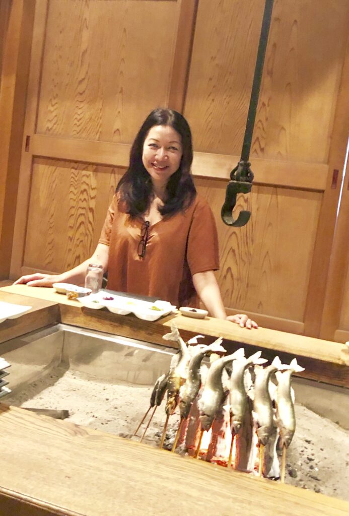 Travelife Magazine Publisher Christine Cunanan dining by the irori hearth at Yanagiya in Gifu, Japan, one of the country’s most exclusive wild-cuisine restaurants, known for seasonal game and river fish grilled over charcoal.