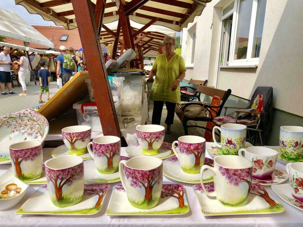 Flea market vendor stall in Hévíz, Hungary — mix of antique linens, old silverware, and inherited treasures.