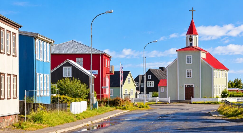 Colorful wooden houses and a red-roofed church in an AI-enhanced illustration of an Icelandic coastal village.
