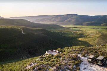 Luxury safari landscape at Bushmans Kloof Wilderness Reserve in South Africa, featuring dramatic sandstone cliffs, vast green plains, and pristine natural scenery in the Cederberg Mountains.