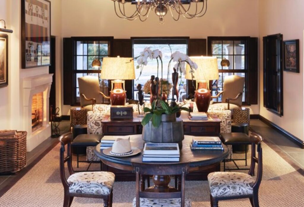 Elegant living room at Cederberg House in Bushman’s Kloof, featuring a warm fireplace, classic wooden furniture, orchids, and soft lighting. The refined interior reflects South African country charm and sophisticated lodge design surrounded by the Cederberg wilderness.