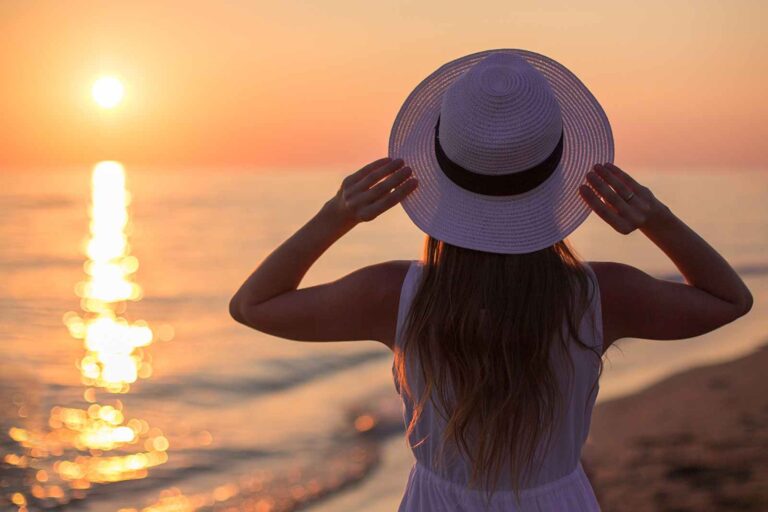 A traveler in a white hat watches the sunset from the deck of a luxury voyage — symbolizing reflection, freedom, and the art of slow travel in the Frequent Flier column of Travelife Magazine.