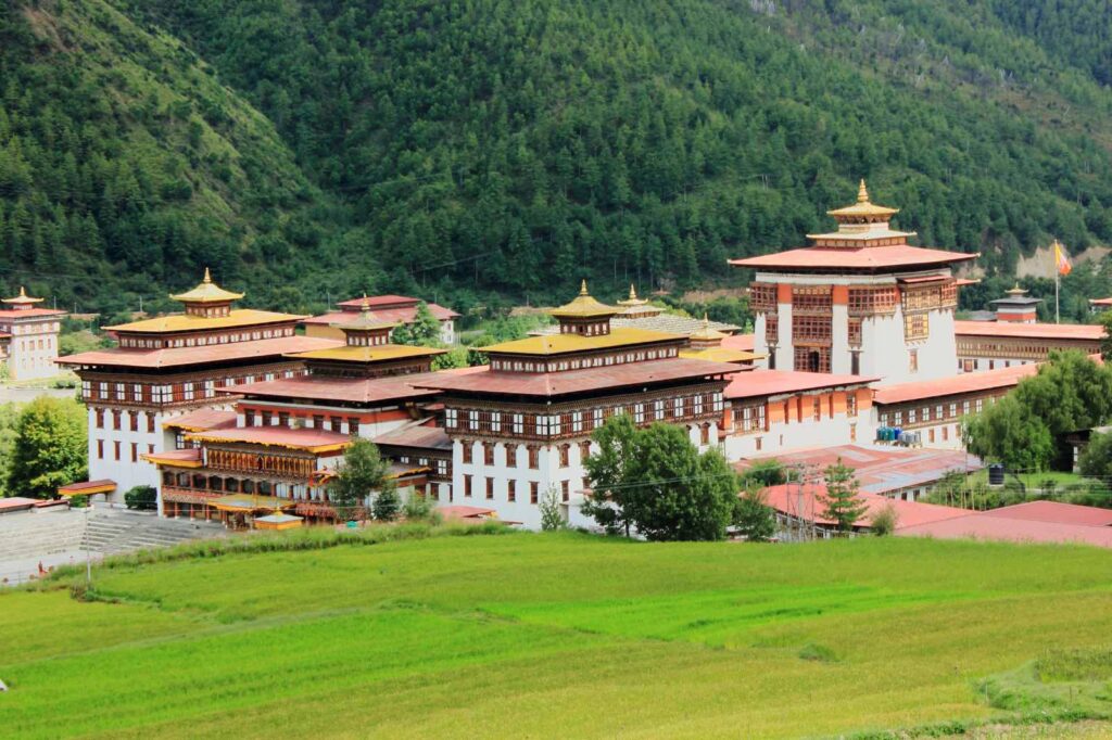 Panoramic image of Tashichho Dzong, Bhutan’s royal and religious center, blending whitewashed walls, red-gold roofs, and Himalayan scenery under a soft mountain light.