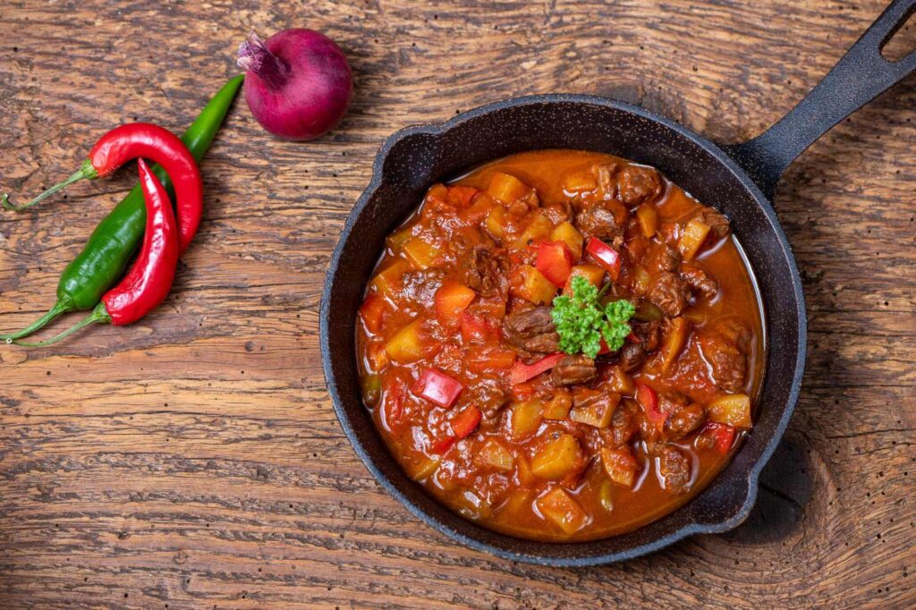 Hot bowl of traditional Hungarian gulyás soup with paprika — best goulash in Budapest.