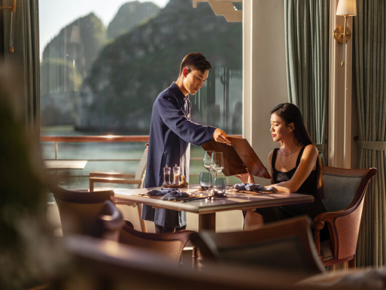 Couple enjoying fine dining with panoramic views of Halong Bay, Vietnam — an unforgettable luxury travel experience curated by Travelife Magazine.