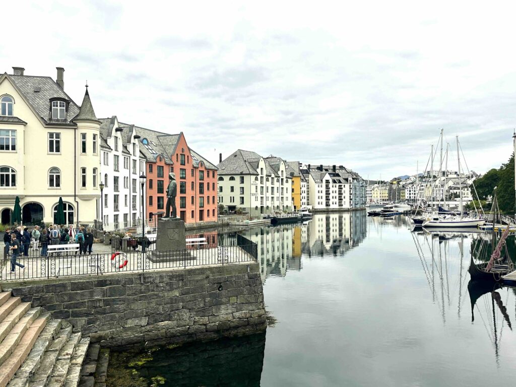 Downtown view of Alesund, Norway, with boats moored at Ålesund harbor and the pastel colored Art Nouveau buildings in the background — classic Norwegian coastal town landscape.