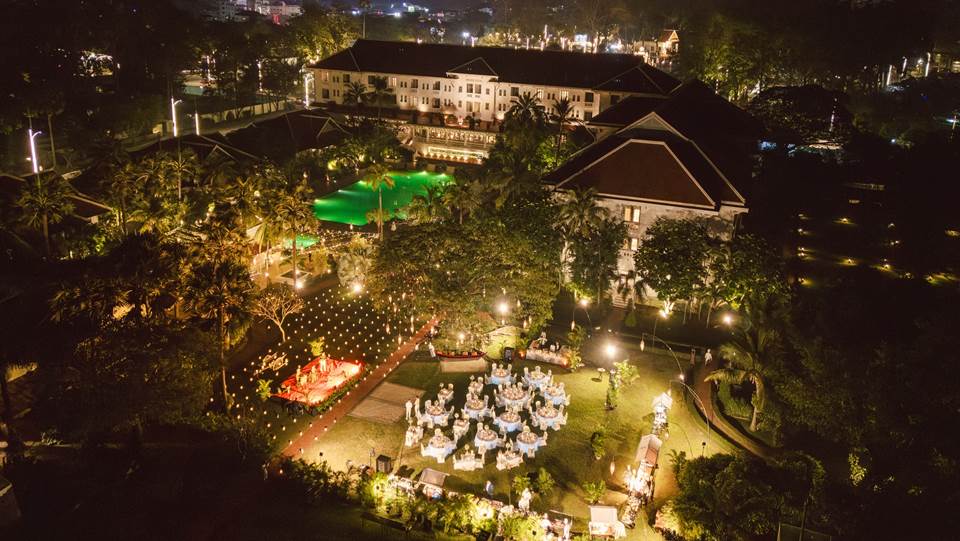 Heritage garden at Raffles Grand Hotel d’Angkor in Siem Reap, featuring manicured lawns, tall tropical trees, and elegant colonial-era architecture in the background.