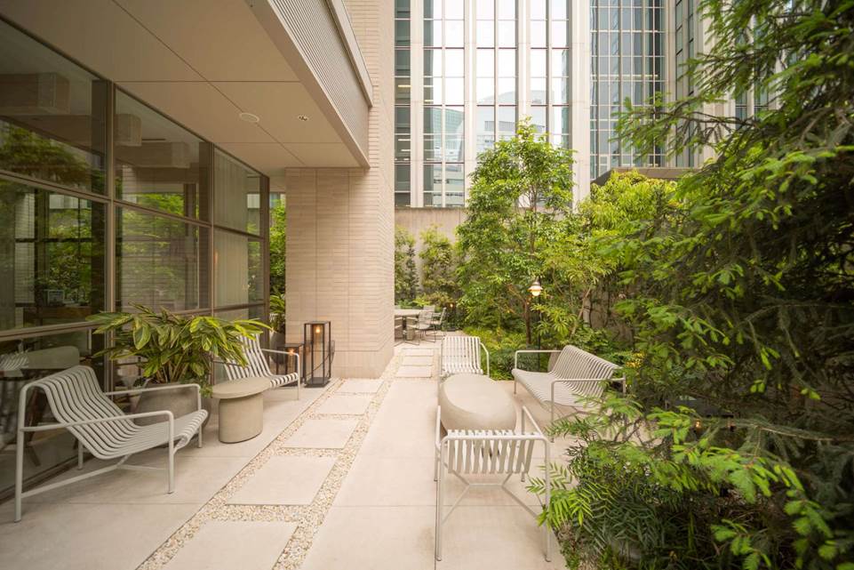 Tranquil garden entrance at Zentis Osaka, with Japanese maple, cherry blossoms, and curated greenery leading to a stone terrace and modern lounge.