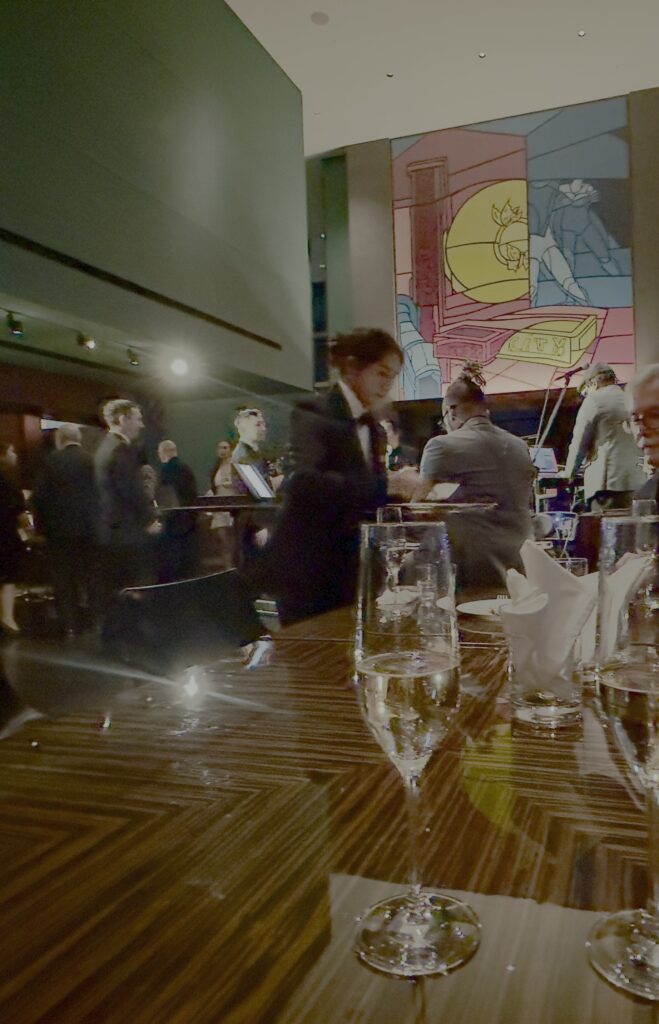 Guests converse over drinks at the New York Grill inside Park Hyatt Tokyo during the hotel’s reopening evening, with Valerio Adami’s bold mural glowing softly in the background — a timeless blend of art, atmosphere, and skyline sophistication.