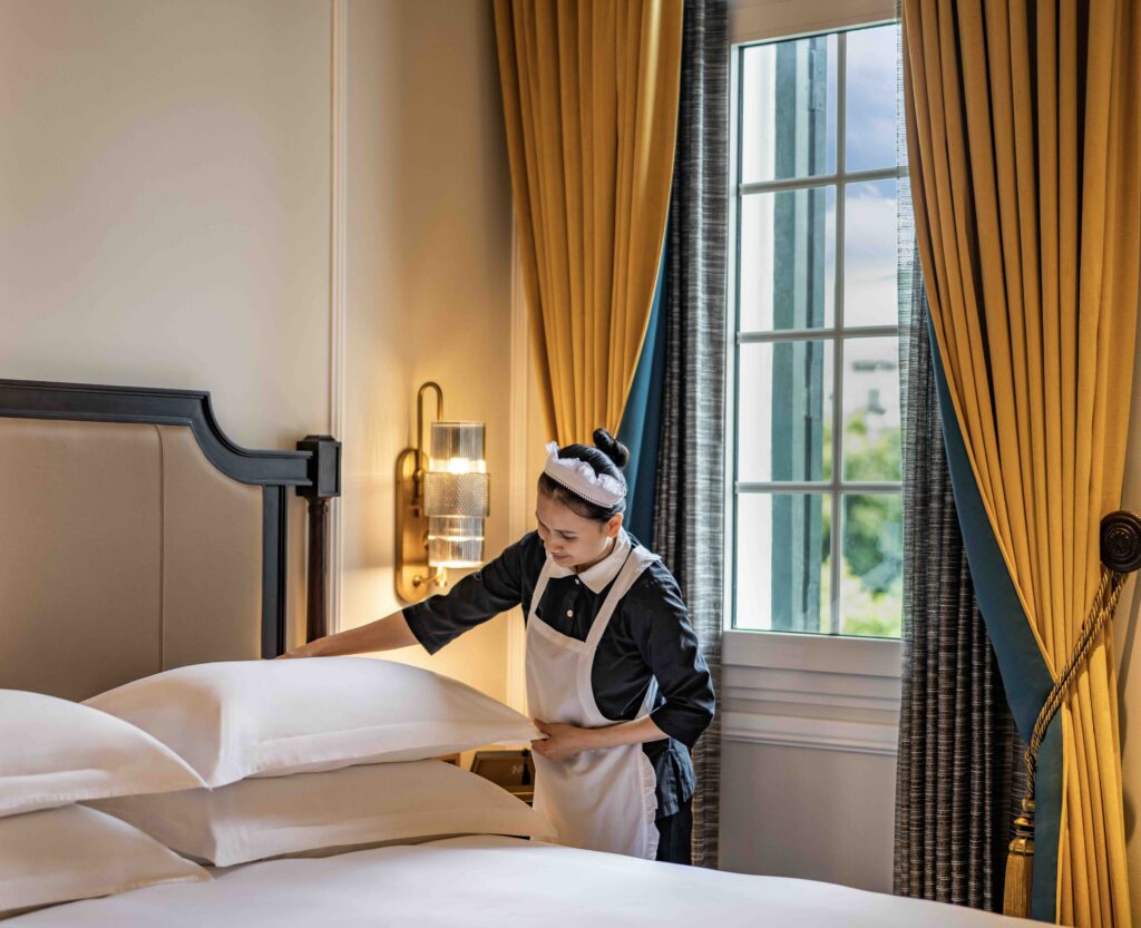 Housekeeper preparing a luxury guest room at Sofitel Legend Metropole Hanoi
