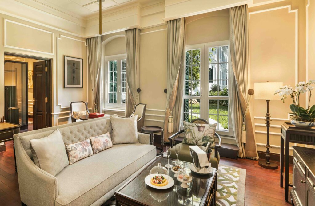 Luxury suite living room at Sofitel Legend Metropole Hanoi featuring elegant furnishings, high ceilings, and garden views
