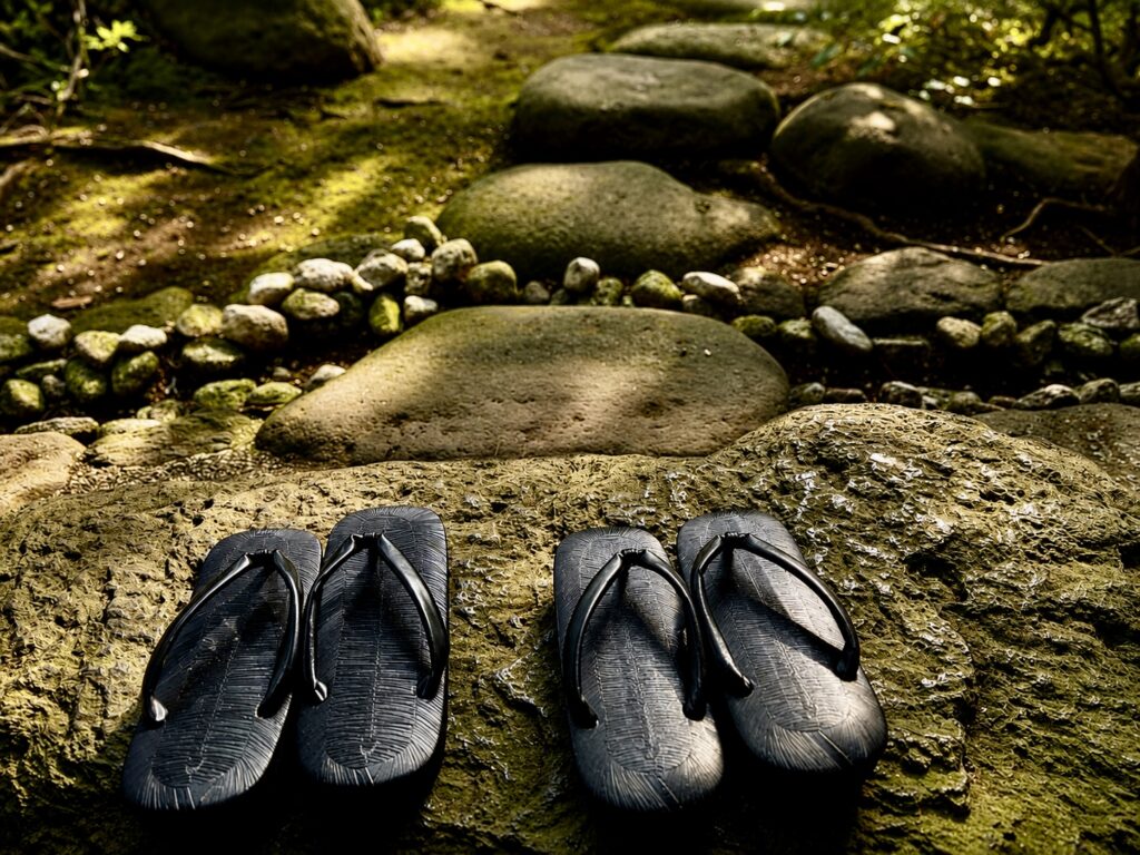 Traditional Japanese wooden geta sandals beside a garden stream at Numazu Club, Shizuoka, Japan, reflecting the property’s tranquil atmosphere and authentic guest experience. Photographed by Travelife Magazine.