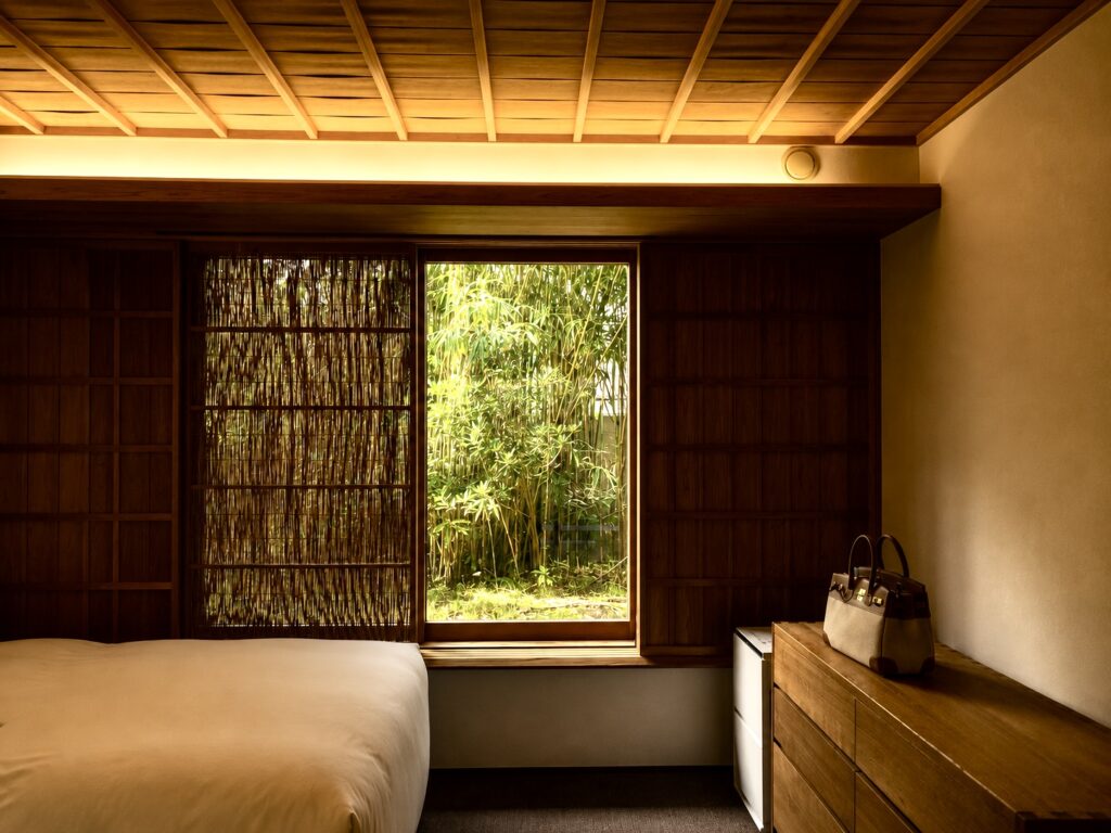 Guest bedroom at Numazu Club in Shizuoka, Japan, with minimalist Japanese design, warm wood finishes, premium bedding, and tranquil garden views. Photographed by Travelife Magazine.