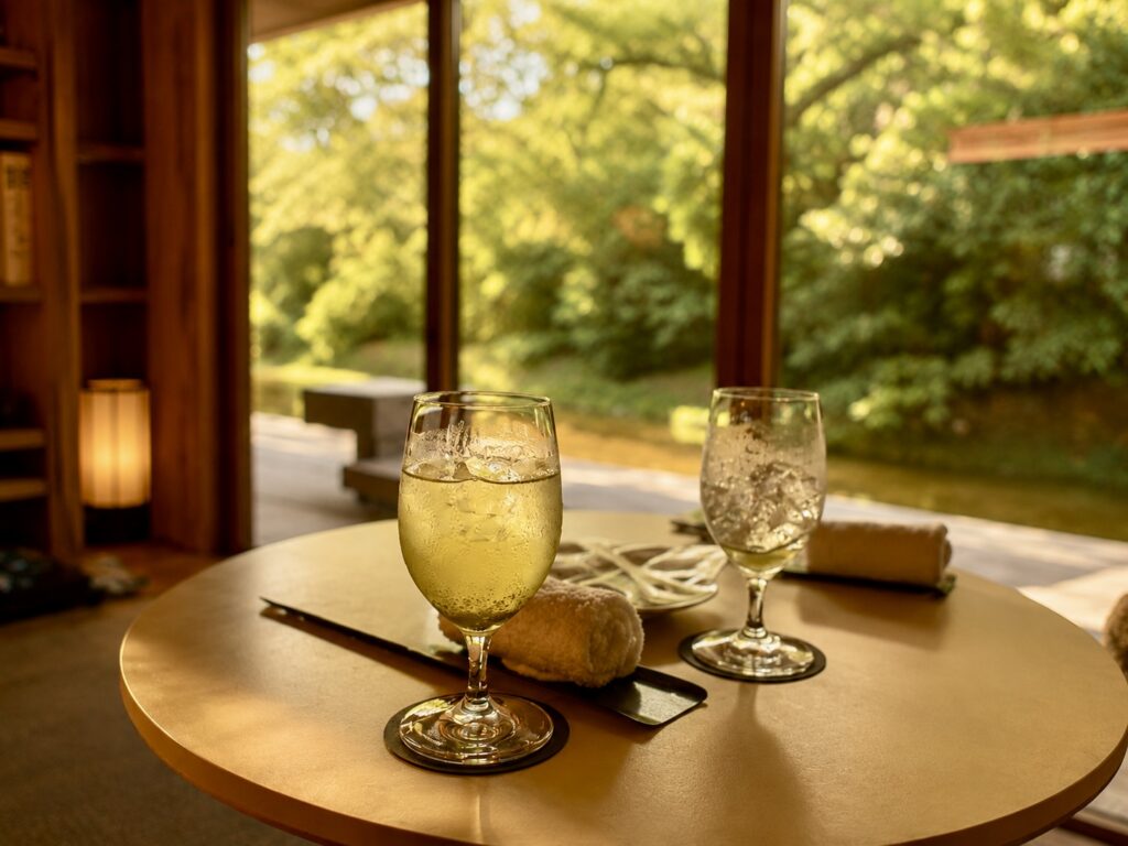 Freshly brewed iced green tea served in a guest suite at Numazu Club in Shizuoka, Japan, with floor-to-ceiling windows overlooking the estate’s peaceful gardens and pond. Photographed by Travelife Magazine.