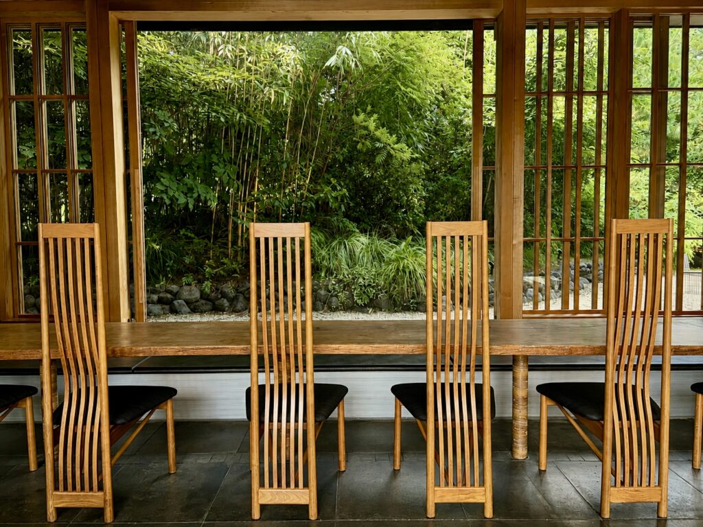 Handcrafted wooden communal table and chairs in the contemporary lobby at Numazu Club, Shizuoka, Japan, with tranquil garden views. Photographed by Travelife Magazine.