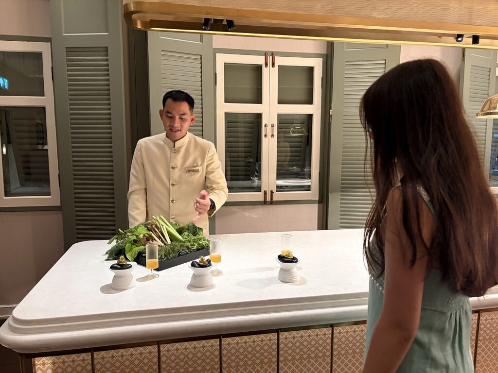 Guest speaking with a member of the dining team at the open kitchen of Baan Phraya, Mandarin Oriental, Bangkok.