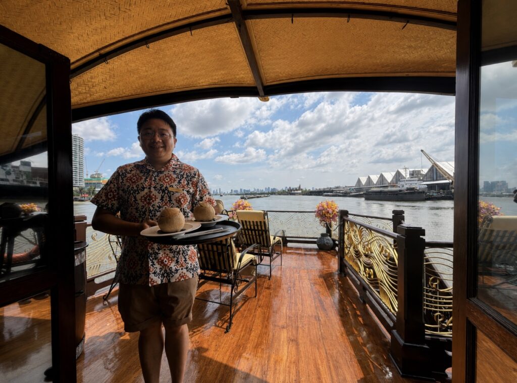 Butler serving fresh coconut juice onboard a Bangkok river cruise to Ayutthaya