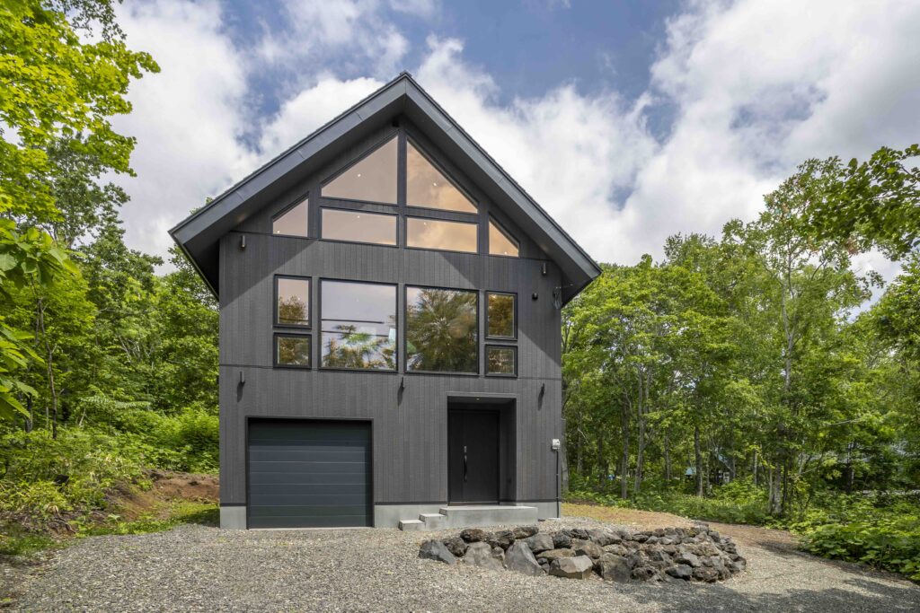 Front exterior of Soga Forest Chalet, a three-bedroom luxury holiday chalet in Niseko, Hokkaido, Japan, surrounded by green forest.
