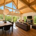 Open-plan living and dining room at Soga Forest Chalet in Niseko, Hokkaido, with vaulted timber ceilings, exposed beams and floor-to-ceiling forest views.