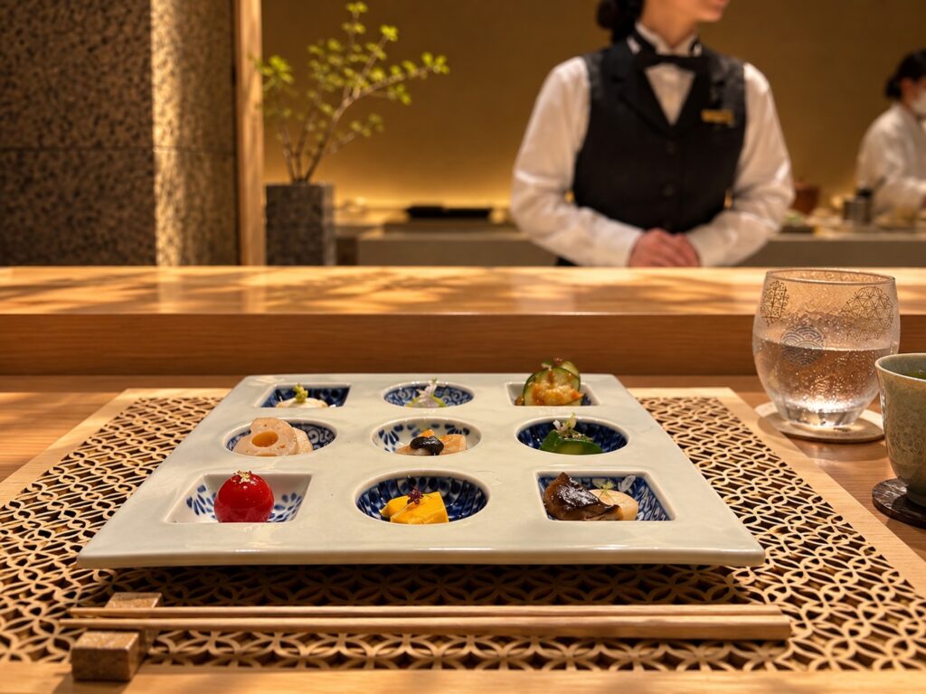 Japanese tasting menu with small, beautifully arranged dishes on a rectangular tray at THE PASONA Natureverse Retreat on Awaji Island, Japan.