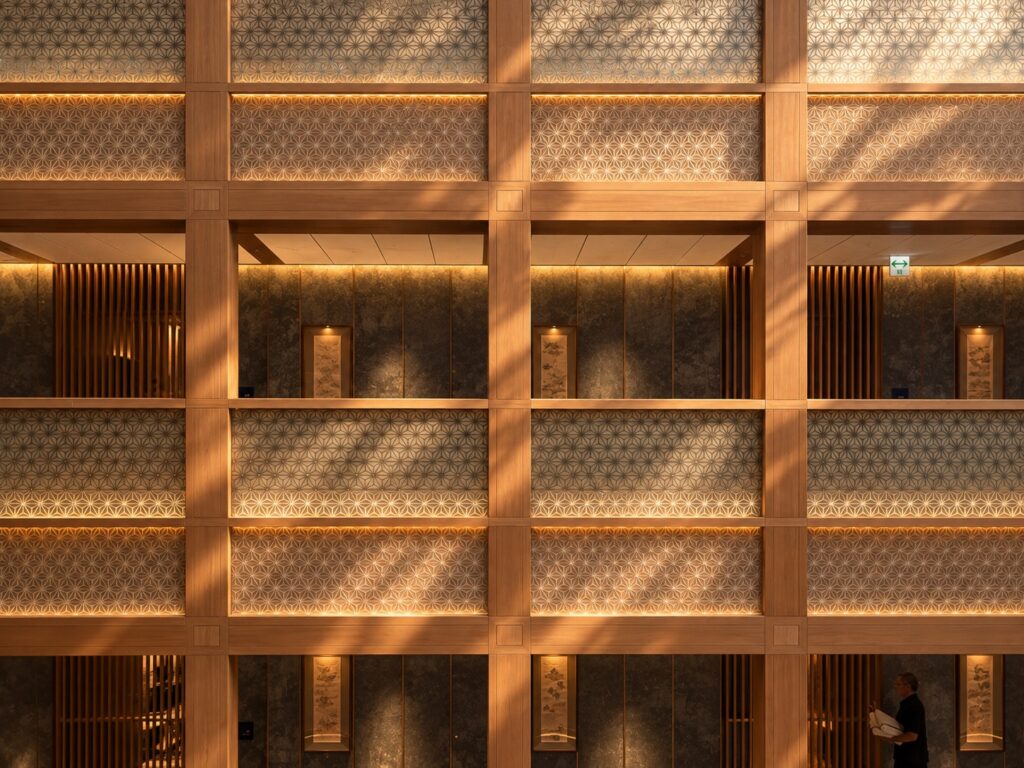 Geometric wooden lattice structure with illuminated recessed panels inside Pasona Natureverse Retreat on Awaji Island, Japan.